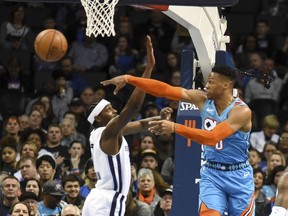 Oklahoma City Thunder guard Russell Wesatbrook, right, passes the ball around Memphis Grizzlies guard Justin Holiday, left, in the first half of an NBA basketball game, Sunday, March 3, 2019, in Oklahoma City.