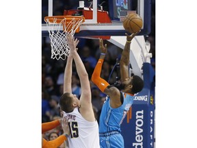 Oklahoma City Thunder forward Paul George, right, shoots in front of Denver Nuggets center Nikola Jokic (15) in the first half of an NBA basketball game Friday, March 29, 2019, in Oklahoma City.