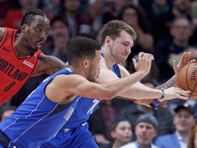 Dallas Mavericks forward Luka Doncic, right, and guard Jalen Brunson, center, reach for a loose ball in front of Portland Trail Blazers forward Al-Farouq Aminu during the first half of an NBA basketball game in Portland, Ore., Wednesday, March 20, 2019.