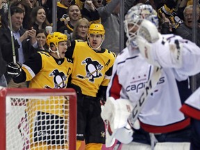 Pittsburgh Penguins' Sidney Crosby (87) celebrates his first of two second period goals with Evgeni Malkin (71) as Washington Capitals goaltender Braden Holtby, right, collects himself during an NHL hockey game in Pittsburgh, Tuesday, March 12, 2019.
