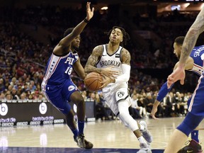 Brooklyn Nets' D'Angelo Russell, center right, drives to the basket as Philadelphia 76ers' Shake Milton defends during the first half of an NBA basketball game, Thursday, March 28, 2019, in Philadelphia.