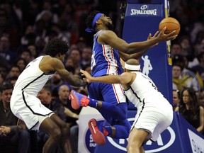 Philadelphia 76ers' Joel Embiid, center, drives to the basket as Brooklyn Nets' Jared Dudley, right, and Ed Davis, left, defend during the second half of an NBA basketball game, Thursday, March 28, 2019, in Philadelphia.