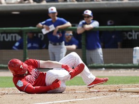 Philadelphia Phillies' Bryce Harper rolls on the dirt holding his leg after getting hit by a pitch against the Toronto Blue Jays during the sixth inning in a spring training baseball game, Friday, March 15, 2019, in Clearwater, Fla. Harper sustained a bruised right foot Friday, but manager Gabe Kapler said the team wasn't overly worries about the injury. Initial X-rays were negative, the team said, but Harper then left the ballpark for more detailed X-rays.