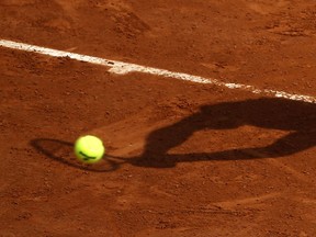 FILE - In this May 28, 2016 file photo, a player's shadow is pictured as he returns the ball during the French Open tennis tournament at the Roland Garros stadium, in Paris. Judicial officials say Thursday March 21, 2019 that French police have questioned another batch of players about their links to an alleged match-fixing syndicate suspected of paying out hundreds of thousands of euros (dollars) to fix low-level tennis matches.