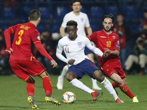 In his debut match for England, Callum Hudson-Odoi, center, vies for the ball with Montenegro's Aleksandar Boljevic, left, and Montenegro's Marko Jankovic, right, during the Euro 2020 group A qualifying soccer match between Montenegro and England at the City Stadium in Podgorica, Montenegro, Monday, March 25, 2019.