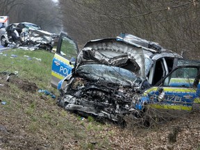 A damaged police car is seen next to a road in Langen near Frankfurt, Germany, Sunday, March 31, 2019. The police car with two police officers was on the way to a nearby plane crash as it collided with another car, background, carrying two young people who died in the crash. The police officers were seriously injured.