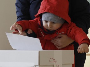 A child casts a vote for her mother at a polling station during the first round of the presidential election in Bratislava, Slovakia, Saturday, March 16, 2019.