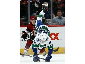 Vancouver Canucks center Adam Gaudette (88) gets upended on a kneeing penalty by Arizona Coyotes' Conor Garland as Coyotes center Christian Dvorak, left, watches the movement of the puck during the first period of an NHL hockey game Thursday, Feb. 28, 2019, in Glendale, Ariz.