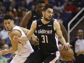 Washington Wizards guard Tomas Satoransky (31) is fouled by Phoenix Suns Devin Booker, left, as Wizards' Thomas Bryant, back, watches during the first half of an NBA basketball game Wednesday, March 27, 2019, in Phoenix.