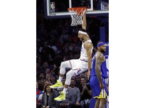 Philadelphia 76ers' Ben Simmons, left, reacts after dunking past Golden State Warriors' DeMarcus Cousins during the first half of an NBA basketball game, Saturday, March 2, 2019, in Philadelphia.