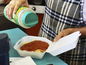 In this Thursday, March 14, 2019 photo, Belinda Lau, manager of the Wiki Wiki Drive Inn takeout restaurant in Honolulu, sprinkles cheese on an order of spaghetti in a styrofoam container. Hawaii would be the first state in the U.S. to ban most plastics used at restaurants under legislation that aims to cut down on waste that pollutes the ocean. Dozens of cities across the country have banned plastic foam containers, but Hawaii would be the first to bar them statewide.