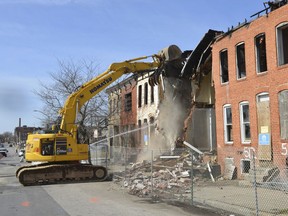 Work crews demolish a derelict block as Baltimore tries to reduce its sea of boarded-up properties, Wednesday, March 13, 2019.   Mayor Catherine Pugh says her administration is committed to eliminating abandoned houses to "pave the way for new investment and long-awaited revitalization." She got in an excavator Wednesday to start the demolition in a blighted swath of West Baltimore.