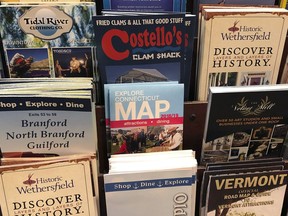 In this Friday, March 29, 2019 photo, pamphlets from various Connecticut tourism attractions are displayed on a rack at the Courtyard Marriott hotel in Norwich, Conn. Lawmakers are considering whether to devote more resources to boost tourism in Connecticut after years of tight budgets. Ideas include devoting more hotel tax revenue for tourism promotion and reopening or expanding the hours of the state visitor welcome centers. There's also a call for overhauling the state's slogan, "Connecticut: Still Revolutionary."