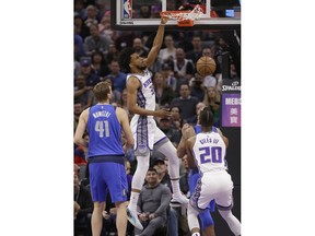 Sacramento Kings forward Marvin Bagley III, center, dunks as Dallas Mavericks forward Dirk Nowitzki, left, and Kings forward Harry Giles III, right, watch during the first quarter of an NBA basketball game Thursday, March 21, 2019, in Sacramento, Calif.