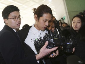 K-pop singer Jung Joon-young, center, arrives at the Seoul Metropolitan Police Agency in Seoul, South Korea, Thursday, March 14, 2019. Police have alleged Jung secretly filmed himself having sex with about 10 women and shared the footage with friends by a mobile messenger app.