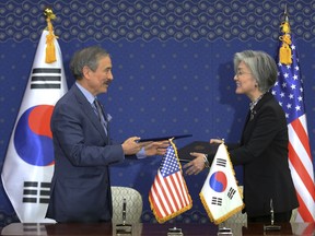 South Korean Foreign Minister Kang Kyung-wha, right, and U.S. Ambassador to South Korea Harry Harris exchange documents at Foreign Ministry in Seoul, South Korea, Friday, March 8, 2019. South Korea and the United States have formally signed a deal that increases Seoul's financial contribution for the deployment of U.S. troops in the Asian country.