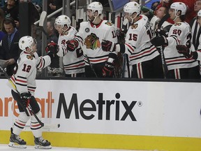 Chicago Blackhawks left wing Alex DeBrincat (12) is congratulated by teammates after scoring a goal against the San Jose Sharks during the first period of an NHL hockey game in San Jose, Calif., Thursday, March 28, 2019.