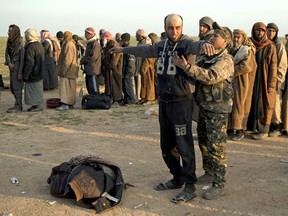 A man is frisked on Feb. 22, 2019, by a Syrian Democratic Forces fighter after being evacuated out of the last territory held by Islamic State militants, near Baghouz, eastern Syria.