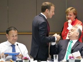 FILE - In this Friday, June 29, 2018 file photo French President Emmanuel Macron, center, greets Hungarian Prime Minister Viktor Orban, right, during a breakfast meeting at an EU summit in Brussels. At rear right is German Chancellor Angela Merkel and left is Irish Prime Minister Leo Varadkar.