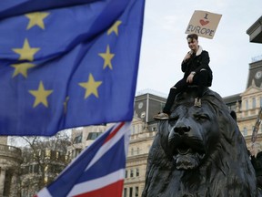 A demonstrator sits on one of the lions in Trafalgar Square during a Peoples Vote anti-Brexit march in London, Saturday, March 23, 2019. The march, organized by the People's Vote campaign is calling for a final vote on any proposed Brexit deal. This week the EU has granted Britain's Prime Minister Theresa May a delay to the Brexit process.
