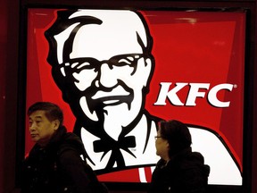 FILE - In this Monday, Feb. 25, 2013,file photo, a Chinese couple walk past a KFC restaurant at a shopping mall in Beijing. The official Xinhua News Agency says fast food chain KFC launched its first "Lei Feng Spirit" restaurant in Lei's home province of Hunan on Tuesday, March 5, 2019, the official remembrance day for the soldier who died in 1962 at the age of 21.