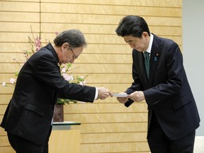 Okinawa Governor Denny Tamaki, left, hands report of result of a local referendum on U.S. base relocation to Japanese Prime Minister Shinzo Abe during their meeting at the latter's official residence in Tokyo, Friday, March 1, 2019. The residents of Japan's southwestern island region of Okinawa rejected a relocation plan for a U.S. military base in a referendum on Feb. 24, increasing pressure on the national government to change its stance that the facility will be built no matter what.