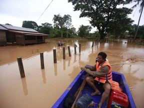 FILE - In this July 26, 2018, file photo, a man paddles his boat through a flooded village after a dam in southeastern Laos collapsed,  in the Sanamxay district, Attapeu province, Laos. A United Nations human rights expert is urging Laos to focus less on big, foreign-invested dam and railway contracts and devote more resources to helping its children and the poor.  Philip Alston, the U.N. rapporteur on poverty, said Laos' economy can only thrive if its leaders do a better job of educating and caring for all of its people.