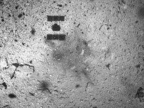 FILE - In this Feb. 22, 2019, file photo, this image released by the Japan Aerospace Exploration Agency (JAXA) shows the shadow, center above, of the Hayabusa2 spacecraft after its successful touchdown on the asteroid Ryugu.  Japan's space agency says its Hayabusa2 spacecraft will follow up last month's touchdown on a distant asteroid with another risky mission -- to drop an explosive to make a crater and collect underground samples to get possible clues to the origin of the solar system. (JAXA via AP, File)