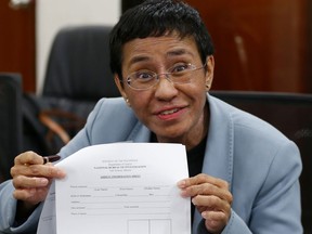 FILE - In this Feb. 13, 2019, file photo, Maria Ressa, the award-winning head of a Philippine online news site Rappler that has aggressively covered President Rodrigo Duterte's policies, shows an arrest form after being arrested by National Bureau of Investigation agents in a libel case in Manila, Philippines. Rappler Inc. reported on Friday, March 29, 2019, its CEO Ressa has been arrested again, this time over an alleged investment violation.