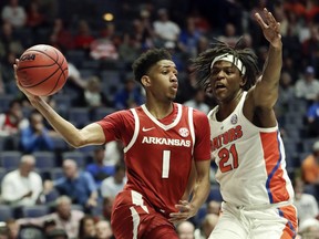 Arkansas guard Isaiah Joe (1) passes around Florida forward Dontay Bassett (21) in the first half of an NCAA college basketball game at the Southeastern Conference tournament Thursday, March 14, 2019, in Nashville, Tenn.