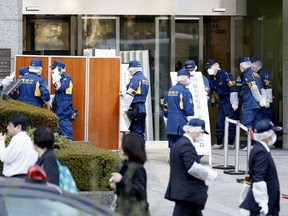 Police investigators inspect the site that a woman was attacked at a court in Tokyo, Wednesday, March 20, 2019.  Police have arrested an American man in an alleged fatal stabbing of his Japanese wife at a Tokyo court where they were reportedly settling a divorce. (Kyodo News via AP)
