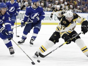 Boston Bruins center Patrice Bergeron (37) flips the puck past Tampa Bay Lightning defenseman Ryan McDonagh (27) during the first period of an NHL hockey game Monday, March 25, 2019, in Tampa, Fla.