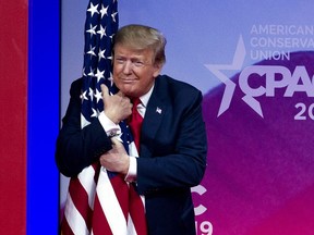 President Donald Trump hugs the American flag as he arrives to speak at Conservative Political Action Conference, CPAC 2019, in Oxon Hill, Md., Saturday, March 2, 2019.