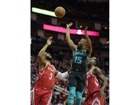 Charlotte Hornets' Kemba Walker (15) shoots as Houston Rockets' Chris Paul (3) and Clint Capela, right, defend during the first half of an NBA basketball game Monday, March 11, 2019, in Houston.