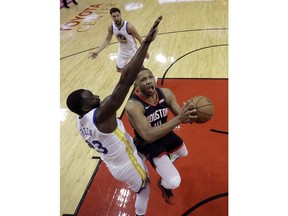 Houston Rockets' Eric Gordon (10) shoots as Golden State Warriors' Draymond Green (23) defends during the first half of an NBA basketball game, Wednesday, March 13, 2019, in Houston.