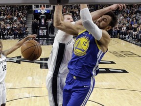 Golden State Warriors center Andrew Bogut (12) is hit across the face as he scores against San Antonio Spurs center Jakob Poeltl (25) during the first half of an NBA basketball game in San Antonio, Monday, March 18, 2019.