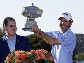 Kevin Kisner, right, holds his trophy presented by Michael Dell, CEO of Dell Technologies, after he defeated Matt Kuchar in the finals at the Dell Technologies Match Play Championship golf tournament, Sunday, March 31, 2019, in Austin, Texas.