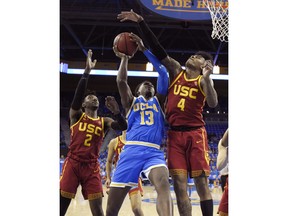 UCLA guard Kris Wilkes, center, shoots as Southern California guard Jonah Mathews, left, and guard Kevin Porter Jr. defend during the first half of an NCAA college basketball game Thursday, Feb. 28, 2019, in Los Angeles.