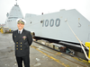 U.S. Navy Capt. Andrew Carlson, commander of the USS Zumwalt, stands in front of the stealth destroyer.