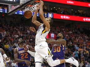Utah Jazz center Rudy Gobert, center, dunks on Phoenix Suns' Deandre Ayton (22) and Troy Daniels (30) during the second half of an NBA basketball game Monday, March 25, 2019, in Salt Lake City.