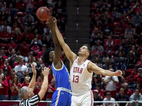 UCLA guard Jalen Hill, center, and Utah forward Novak Topalovic (13) jump for the ball in the first half of an NCAA college basketball game Saturday, March 9, 2019, in Salt Lake City.