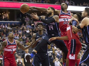 Orlando Magic guard D.J. Augustin (14) shoots between Washington Wizards guard Bradley Beal, left, Magic forward Jonathan Isaac, Wizards forward Jeff Green (32) and guard Chasson Randle and Magic center Nikola Vucevic during the first half of an NBA basketball game Wednesday, March 13, 2019, in Washington.