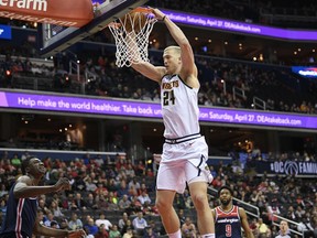 Denver Nuggets forward Mason Plumlee (24) dunks against Washington Wizards center Thomas Bryant, bottom left, and guard Chasson Randle (9) during the first half of an NBA basketball game Thursday, March 21, 2019, in Washington.