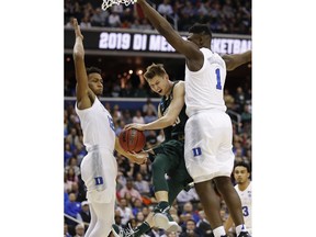 Michigan State guard Matt McQuaid (20) is stopped under the basket by Duke forwards Zion Williamson (1) and Javin DeLaurier (12) during the first half of an NCAA men's East Regional final college basketball game in Washington, Sunday, March 31, 2019.