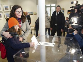 Opposition candidate for the role of Gdansk Mayor Aleksandra Dulkiewicz,second left, poses, with her daughter who casts Dulkiewicz's ballot, in a by-election, in Gdansk, Poland, Sunday, March 3, 2019. Residents in Poland's northern city of Gdansk voted Sunday in a by-election to choose the successor to late Mayor Pawel Adamowicz, who was fatally stabbed during a charity event.