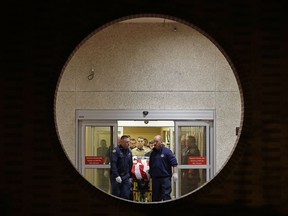 The body of a Kittitas County Sheriff's deputy is draped with a U.S. flag as it is carried out of Kittitas Valley Healthcare Hospital in the early morning hours of Wednesday, March 20, 2019, in Ellensburg, Wash., as seen through a large circular entry window. A sheriff's deputy was killed and a police officer was injured after an exchange of gunfire during an attempted traffic stop.