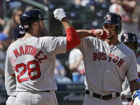 Boston Red Sox's J.D. Martinez, left, is greeted by Xander Bogaerts, right, after hitting a three-run home run during the fourth inning of a baseball game against the Seattle Mariners, Sunday, March 31, 2019, in Seattle.