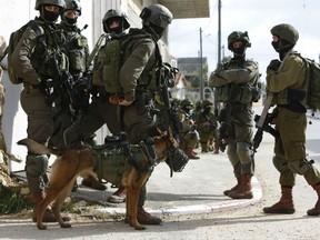 Israeli forces search for a Palestinian gunman in the village of Bruqin near the West Bank town of Salfit, Sunday, March 17, 2019. The Israeli military says a Palestinian killed an Israeli and seriously wounded two others in a West Bank shooting and stabbing spree before fleeing and setting off a massive manhunt.