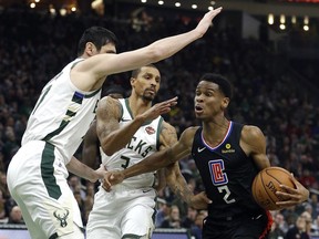 Los Angeles Clippers' Shai Gilgeous-Alexander (2) drives to the basket against Milwaukee Bucks' Ersan Ilyasova and George Hill during the first half of an NBA basketball game Thursday, March 28, 2019, in Milwaukee.