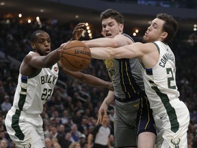 Indiana Pacers' T.J. Leaf, middle, fights for a loose ball with Milwaukee Bucks' Khris Middleton, left, and Pat Connaughton, right, during the first half of an NBA basketball game Thursday, March 7, 2019, in Milwaukee.